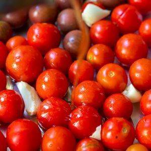 Xếp cà chua vào khay nướng, rắc muối, tỏi, húng quế, lá oregano, lá hương thảo xem kẽ với cà chua, rưới đều dầu olive